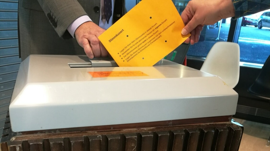 Stimmcouvert wird in Urne geworfen
